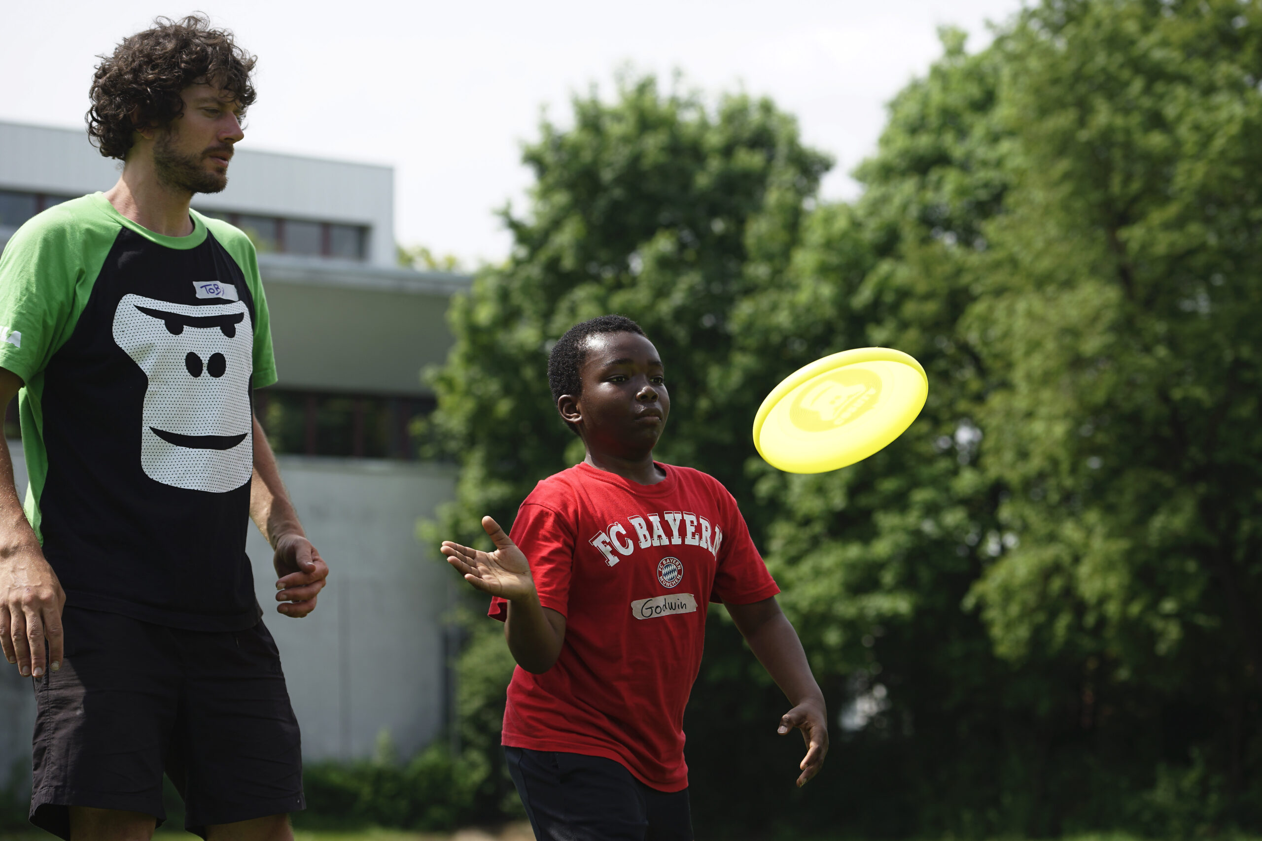Ein GORILLA Botschafter zeigt einem Junge wie man Frisbee spielt im Rahmen eines GORILLA Workshops.