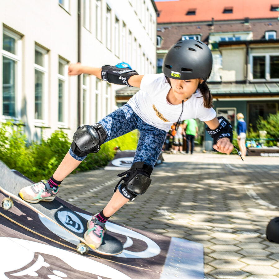 Ein Maedchen faehrt mit dem Skateboard die Anfahrt des GORILLA Playgrounds hoch.