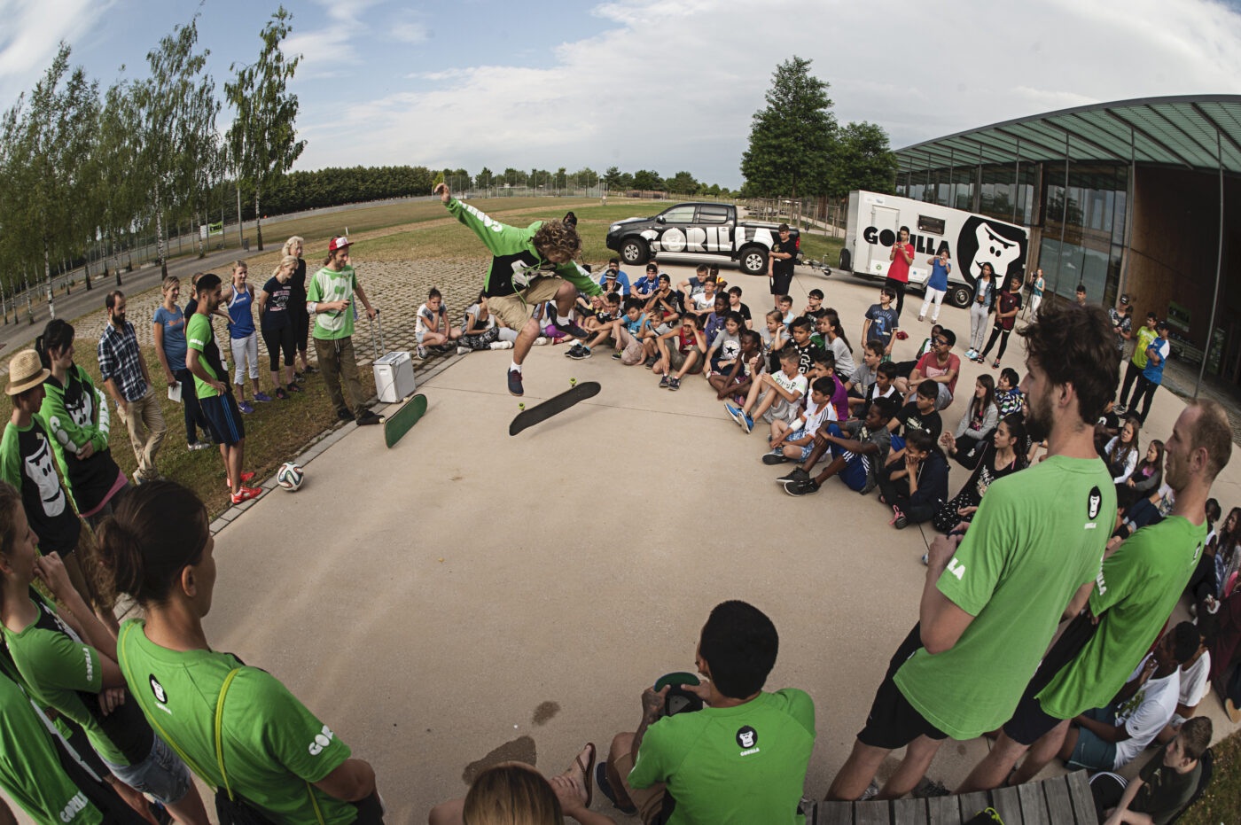 Ein GORILLA Botschafter zeigt in einem Kreis von Jugendlichen einen Skateboardtrick.